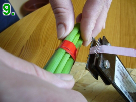 Jehly vázacího stroje nejprve přepíchnou vázací pásku a zoubkovaný nůž tuto pásku odřeže.